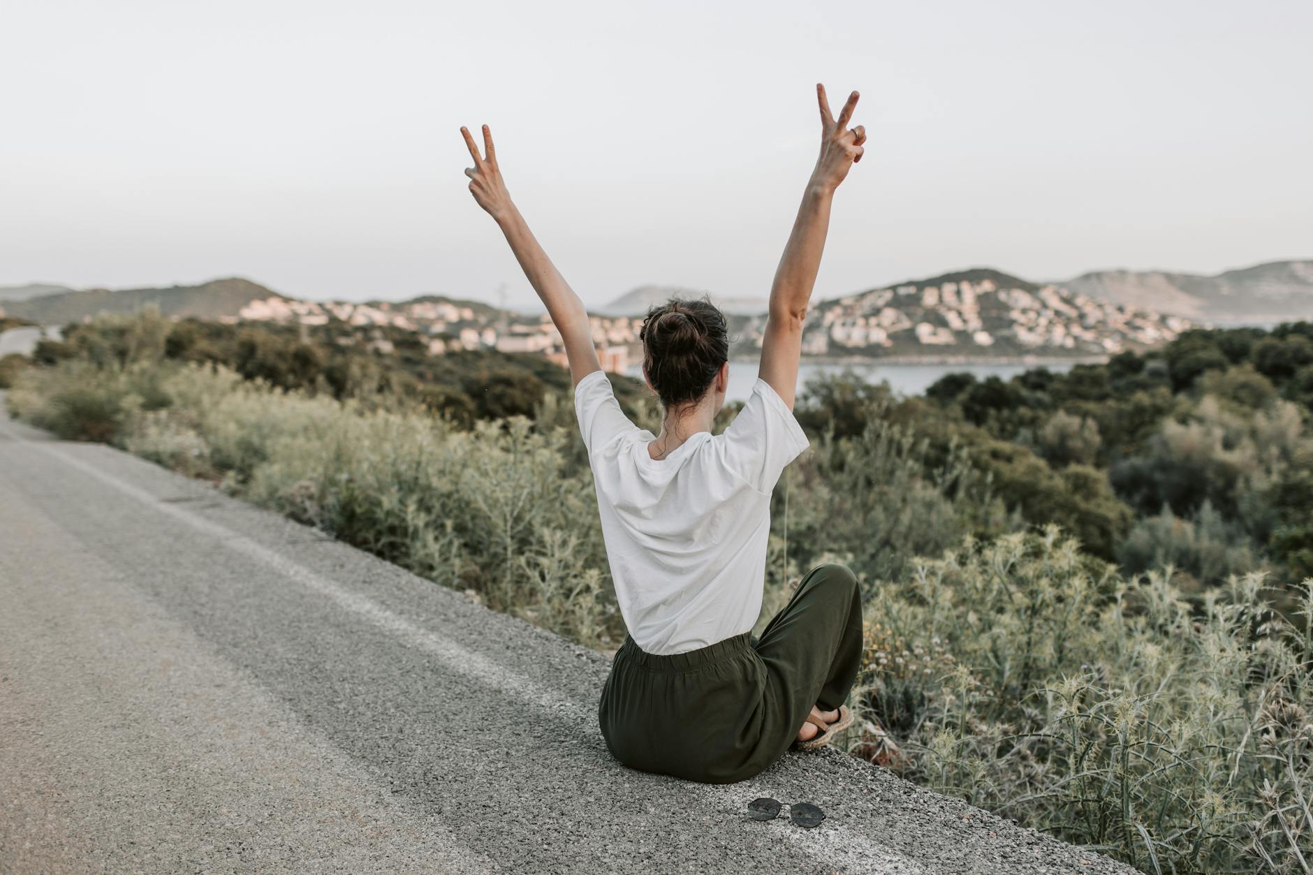 Photo by Vlada Karpovich on <a href="https://www.pexels.com/photo/woman-sitting-on-the-road-making-a-peace-sign-7902950/" rel="nofollow">Pexels.com</a>