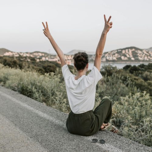 Photo by Vlada Karpovich on <a href="https://www.pexels.com/photo/woman-sitting-on-the-road-making-a-peace-sign-7902950/" rel="nofollow">Pexels.com</a>
